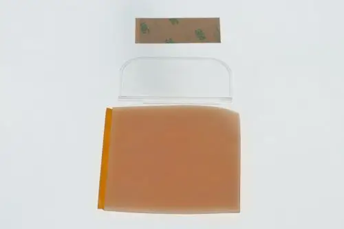 Transparente Isolierplatte von Bosch liegt flach auf einer weißen Oberfläche, daneben ein kleines Stück Klebeband. Die Platte hat abgerundete Ecken und eine orangefarbene Unterseite.
